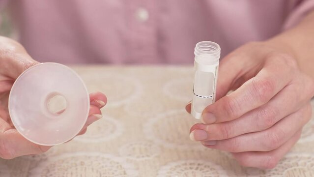 a woman holds in her hands a tube to collect saliva for a DNA test. 