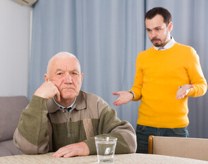 Elderly father and his son are serious conversation at home and solve problems