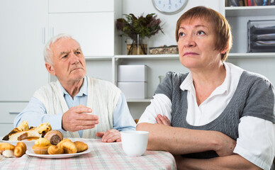 Old couple quarreled and offended at each other at table at home