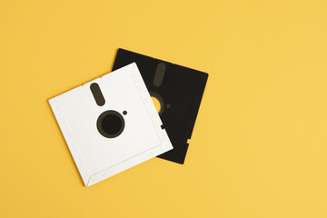 two old-style floppy disks on a yellow background, retro storage media, a disk for a computer of...
