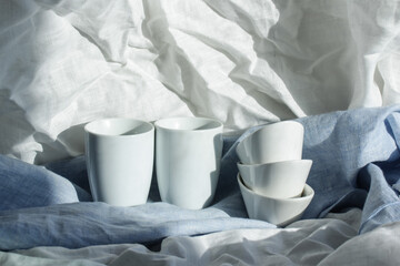 Espresso cups and sugar bowls stand on the table covered with linen tablecloths after washing.