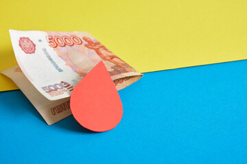 banknote of 5000 rubles, paper blood drop on ukrainian flag colors backgound