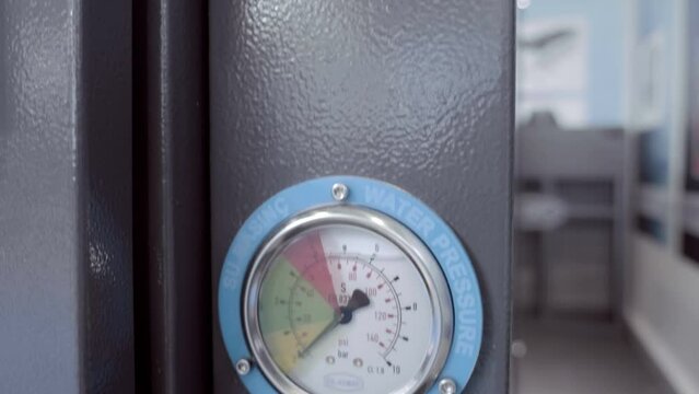 Classic round white dial of a pressure gauges with limits of low, working and dangerous pressure on industrial equipment. Closeup. Shot in motion