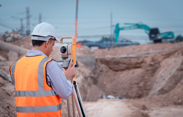 Surveyor engineer wearing safety uniform ,helmet and radio communication with equipment theodolite...