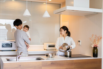 キッチンで料理をするお母さんとお父さんと赤ちゃん