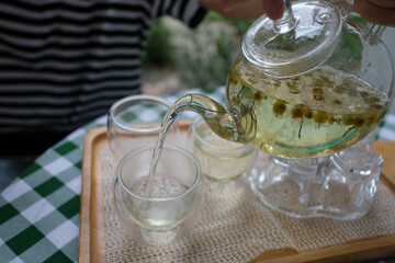 Fototapeta na wymiar Pouring Chamomile tea from teapot into cup