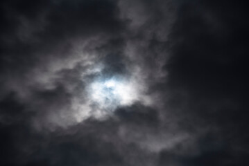 A dark blue sky with clouds and a bright light in the center. Concept - bad weather, bad season at...
