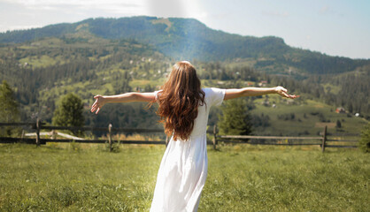 Happy young woman is turning round in the field. Freedom feeling in the mountain
