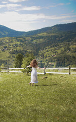 Naklejka na ściany i meble Happy young woman is turning round in the field. Freedom feeling in the mountain