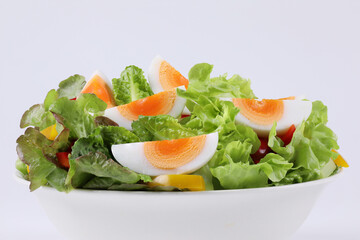 Mixed Vegetable salad with boiled eggs in a bowl. Healthy green salad with boiled eggs and vegetables isolated on white background. Sliced boiled eggs. Healthy food. Hydroponics vegetables.