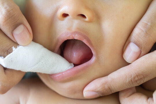 Mother cleans the teeth of a little boy, him to reduce pain from erupting , baby teethfingertip brush for children,  Clean cloth fter bathing at home, Asian family, hygiene. Zoom Selective focus