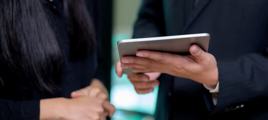 Closeup hands of business team man and woman standing and talking about marketing on tablet with social network at the office, secretary report with executive for planning marketing, business concept.