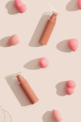 Makeup liquid foundation nude cream cosmetic bottle, , beauty blender, sponges, make up puff on beige background with dark shadows. Tonal bb cream for nude skin color, trend pattern