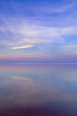 Obraz premium Beautiful sunset on sea, pastel colors and reflections on water, calm nature landscape with colorful clouds
