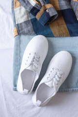 White sneakers close up on white sheet and blue jeans background