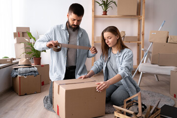 Man and woman packing on moving day. guy sealing a cardboard box with tape, moving and relocation concept