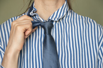 Close up of a young girl in a striped blue shirt and tie, business clothes, an office worker in a...