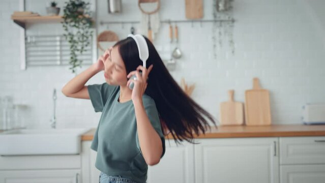 Slow motion of happy young asian woman dancing with headphones at home having fun relaxing with funny dance moves enjoying freedom on weekend morning. People, Lifestyle and joy concept.