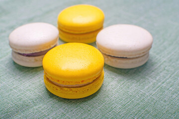 Sweet and bright banana macarons with chocolate filling on a green background. French dessert.