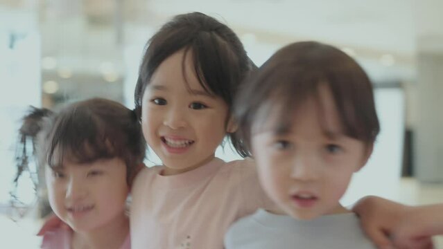 ４歳児の男の子と女の子が仲良く肩を組んで跳ねているポートレート