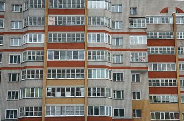 Многоэтажный жилой дом из серого кирпича с оранжевыми и красными лоджиями и балконами.