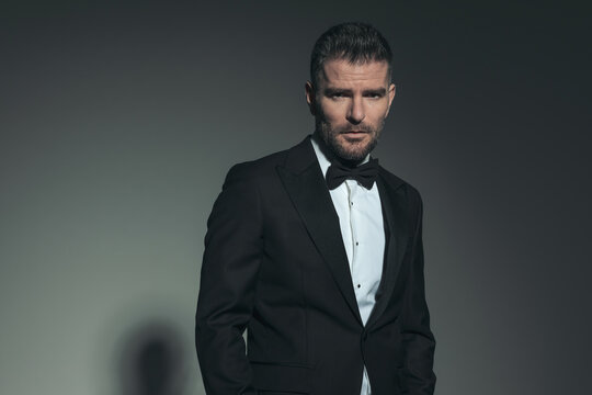 attractive man in his forties wearing black tuxedo and posing