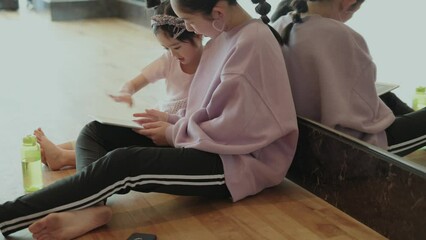 デジタルタブレットで遊んでいる小学生と幼児の女の子 - Powered by Adobe