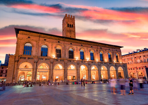 Tourists enjoing beautiful summer evening on main square of City of Bologna with popular historical place - Palazzo Re Enzo. Splendid cityscape of Bologna, Italy. Traveling concept background.
