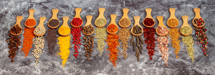 A set of spices on a gray background. Variety of spices from India. Food decoration design. Various spices, peppers and herbs close-up top view. Set of peppers, salt, herbs and spices for cooking. - obrazy, fototapety, plakaty