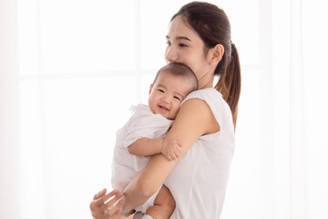Beautiful Asian mother hold and embrace her todlder, mom looking her baby with love and tender,...
