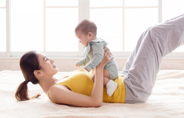Asian mother workout after delivery newborn baby. Beautiful woman and toddler infant play together...