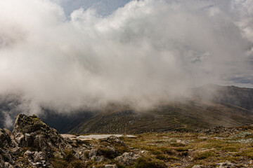 Fog hovering over alpine mountain ranges on winters day. Misty cloud covering mountain valley from summit