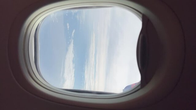 Airplane window looking at the clouds in the sky during flight. Vertical