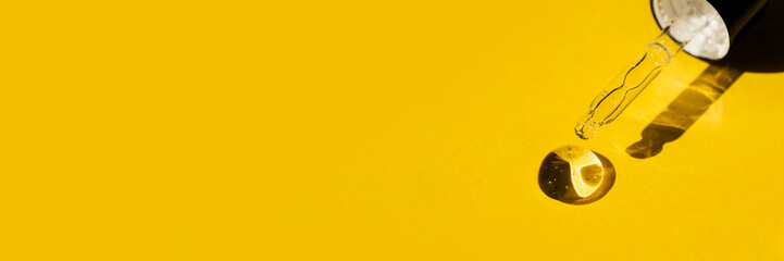 Open cap with close-up dropper pipette with drops of serum. Yellow background with daylight and the...
