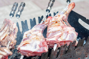 raw lamb meat - legs and ribs, doused with soy sauce, skewered on skewers lie on the grill.