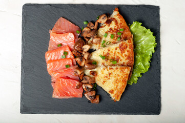 traditional Swiss dish is a sliced potato pancake with pieces of red salmon fish and fried...