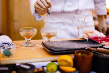 Cook in apron adding some sauce to dish. Cropped chef preparing food, meal, in kitchen, chef cooking, Chef decorating dish, closeup