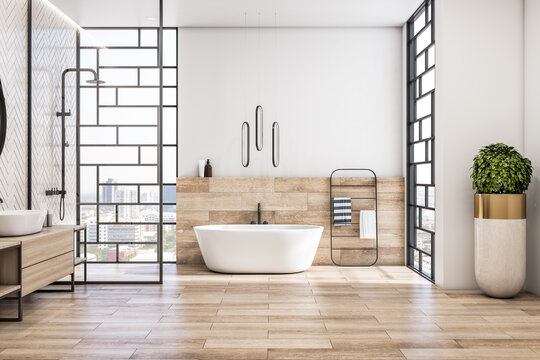 Front view on modern interior design of light bathroom with city view from stylish windows, white bath, wooden floor and sink base cabinet, black shower and green tree in floor vase. 3D rendering