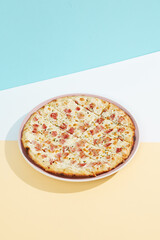 Italian pizza with bacon and cheese on coloured background. Cheese focaccia with bacon in minimal style on blue colour. American pizza delivery concept with color backdrop