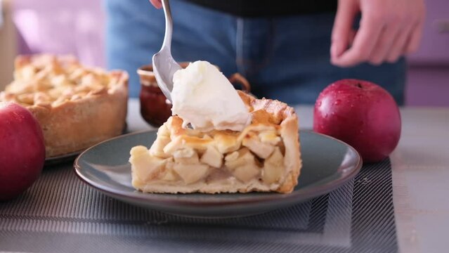 Apple pice cake preparation series - woman puts a spoon of ice cream on top of piece of cake