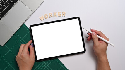 Female office worker holding stylus pen and writing on digital tablet. Above view