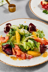 Healthy food - salmon salad with vegetables, greens and citrus. Summer salad with salmon, beetroot, orange and citrus dressing on concrete background. Summer menu in minimal style. Aesthetic food.