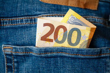 A 200 Euro banknote with the Euro symbol in the pocket of a pair of jeans. Concept about savings, wealth, profits, investments or the use of cash. - obrazy, fototapety, plakaty