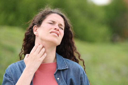 Overwhelmed woman scratching itchy neck in a park