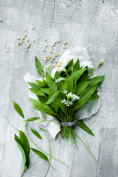 Studio shot of fresh ramson leaves and pine nuts lying against wooden surface