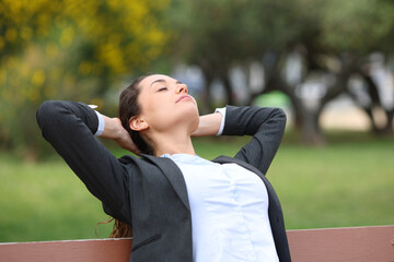 Businesswoman relaxing resting on a bench in a park