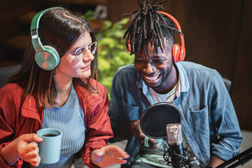 Multi-ethnic couple of YouTubers talking on the microphone making a vlog episode of their streaming video blog - concept of young people create online content for social network platforms