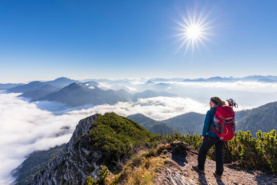 Germany, Bavaria, Female hiker standing on mountaintop admiring fog shrouded peaks of Bavarian Prealps