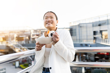 Happy businesswoman eating salad leaning on railing