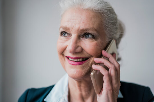 Happy senior businesswoman talking on mobile phone against white background